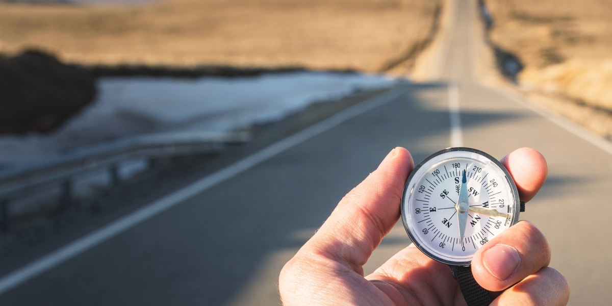 Holding compass in hand standing on highway