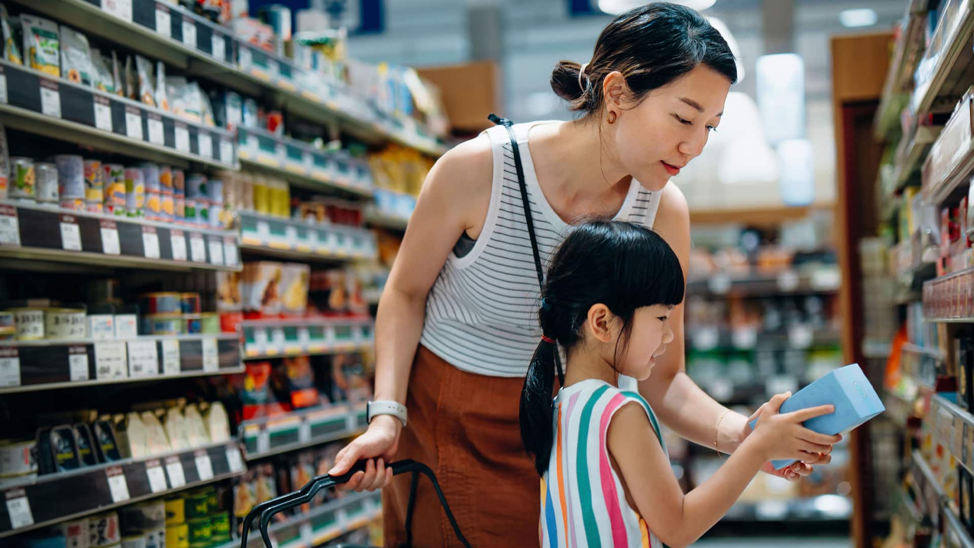 A mother and daughter shopping together at the grocery store.