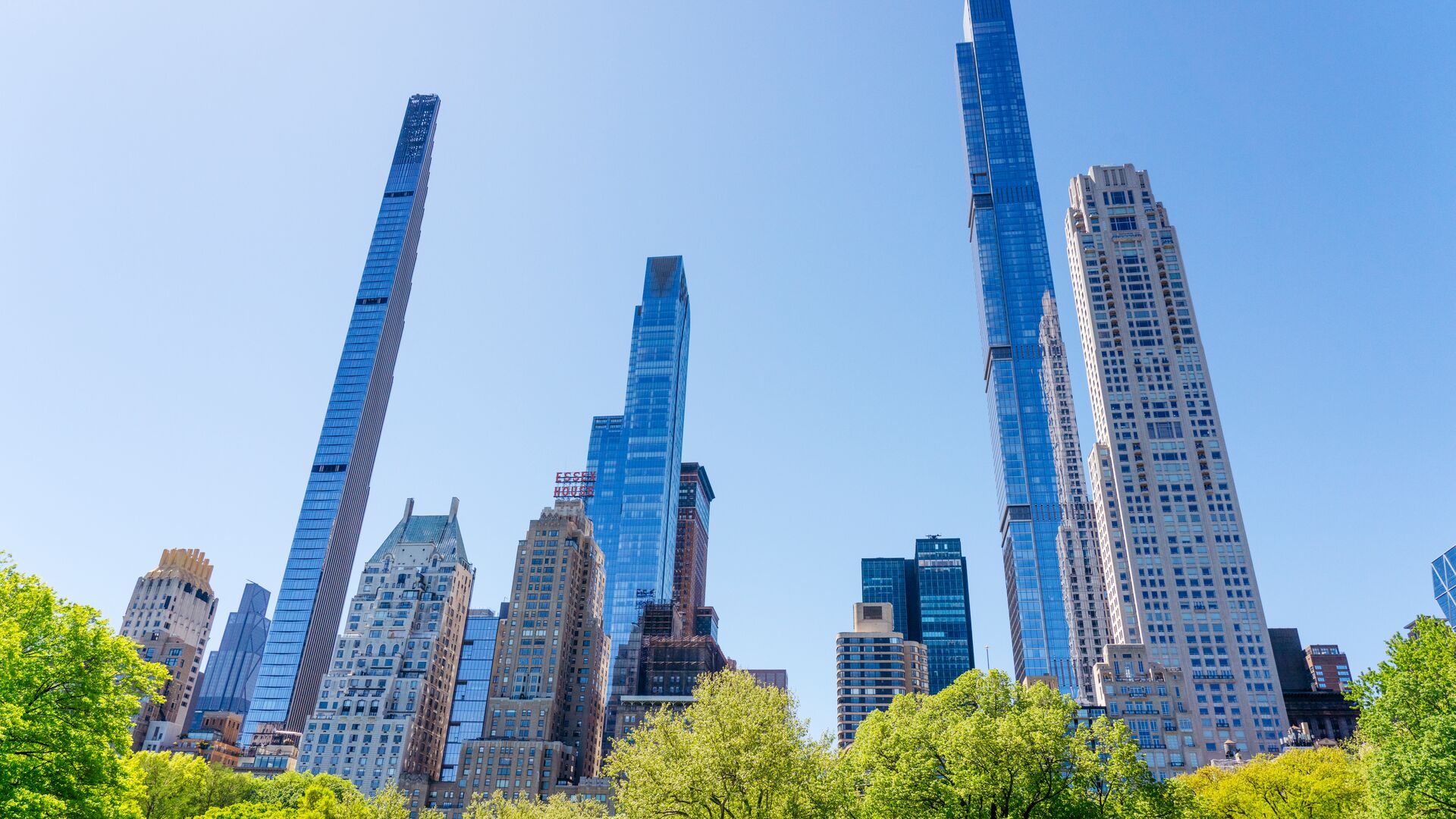 View of Midtown Manhattan skyscrapers rising above the trees of Central Park on a clear day.
