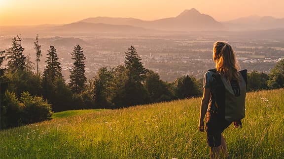 A woman on a hike in a large valley surrounded by mountains.