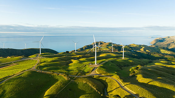 Beautiful scenic view of windmills scattered across the hills with coast in background.