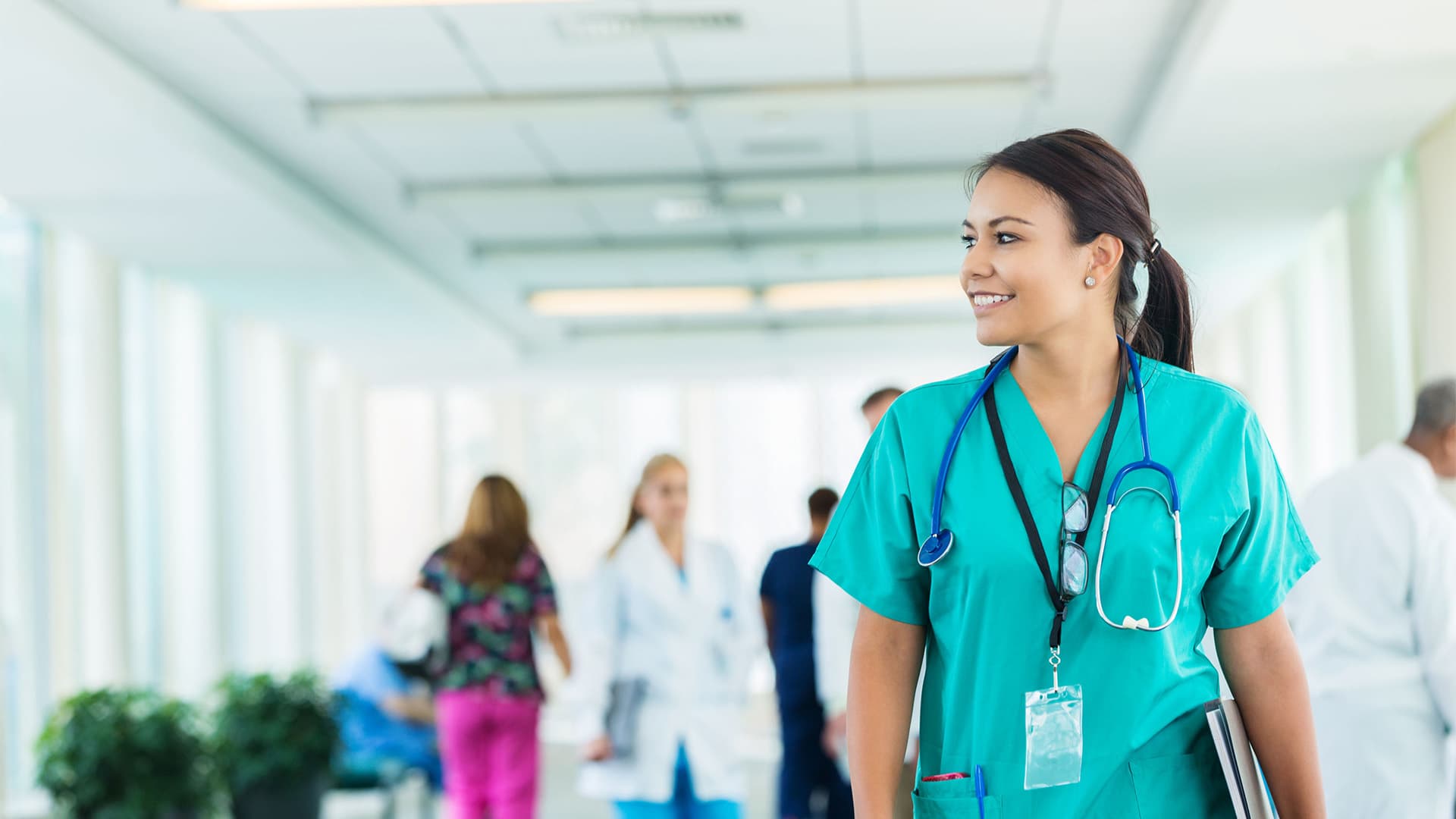 A nurse wearing scrubs, stethoscope, glasses and id badge.