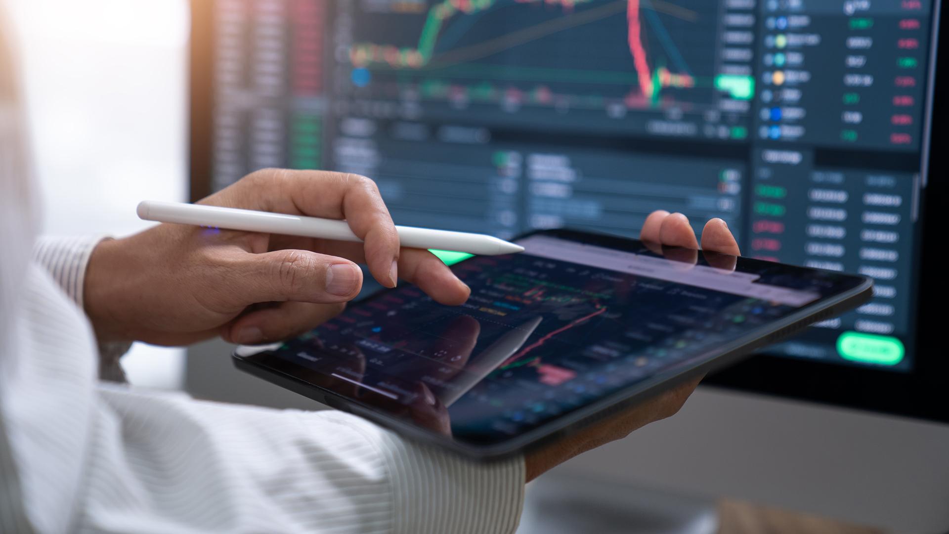 A person looking at staffs and graphs on multiple screens.