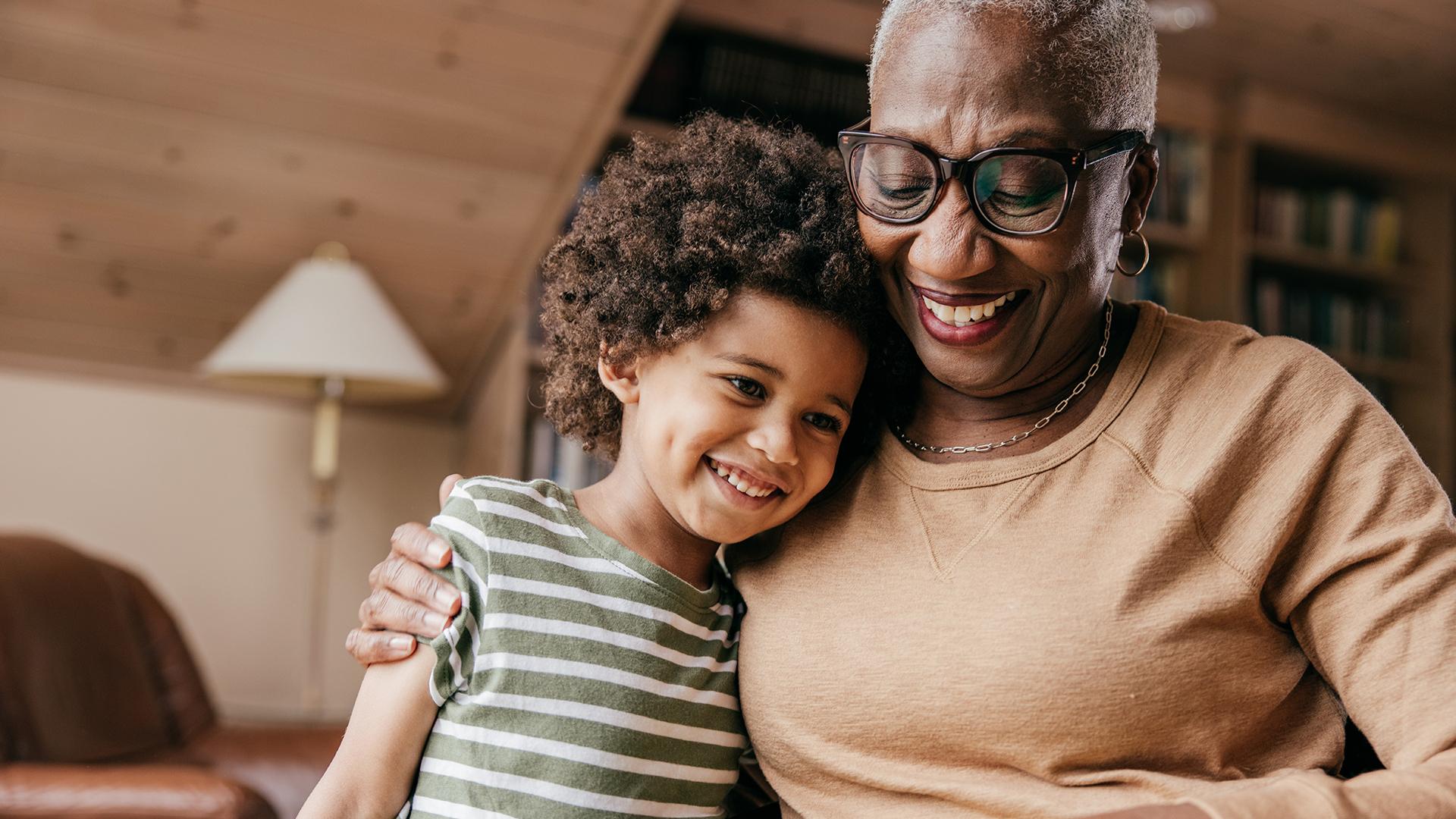 A grandmother and grandson that are smiling and hugging each other