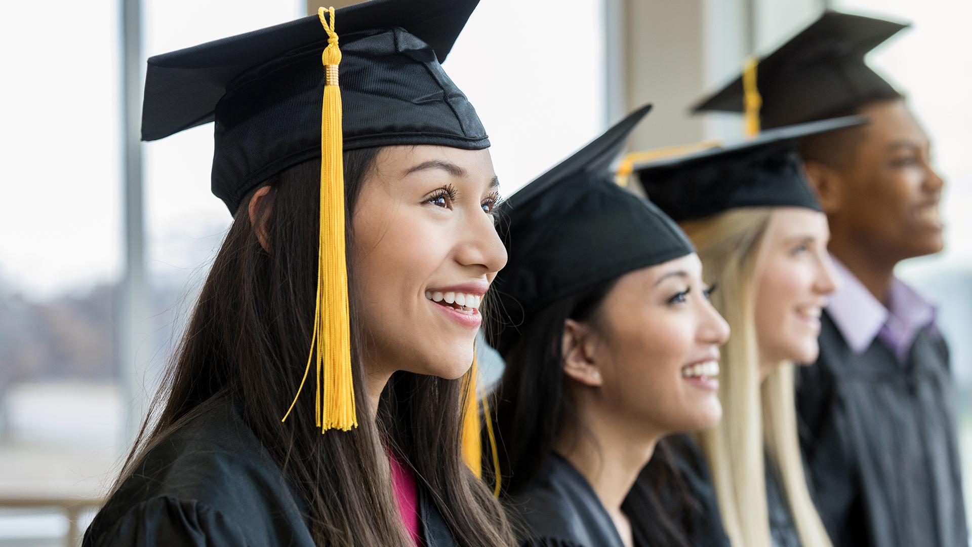 Woman wearing graduation cap and gown with peers.