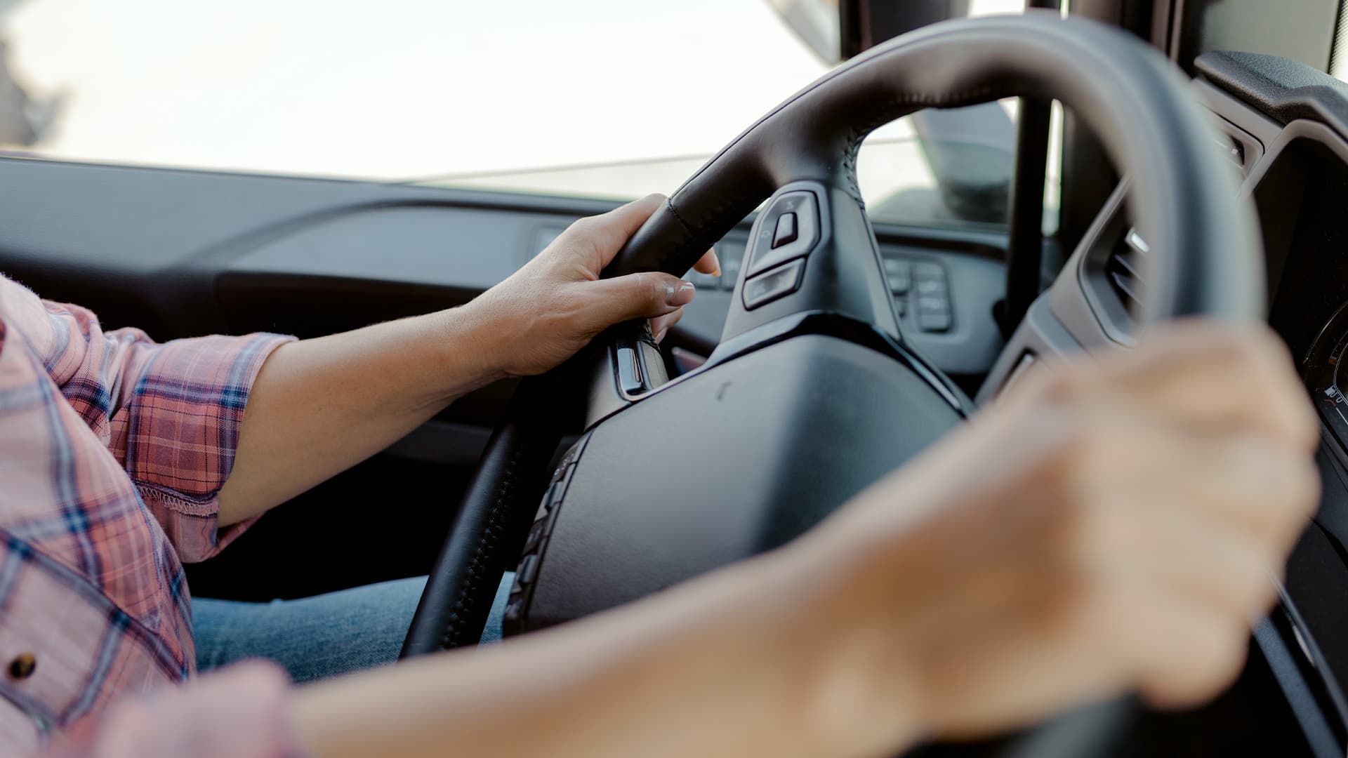 A person in a vehicle holding on to the steering wheel with both hands