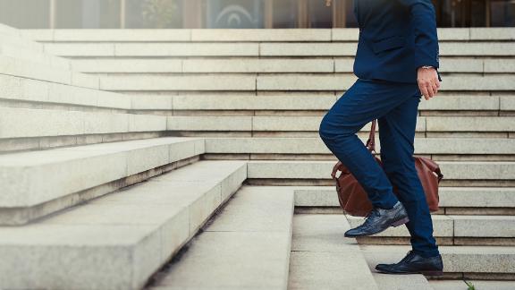 A businessman walking up steps to get to work in the city