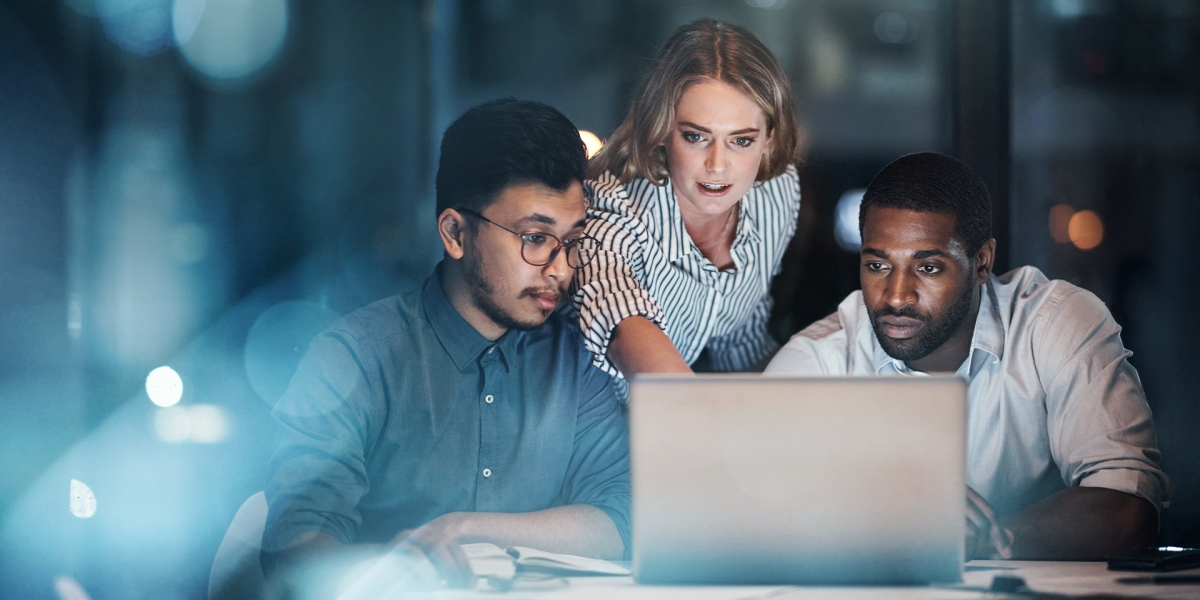 three coworkers looking at a laptop together