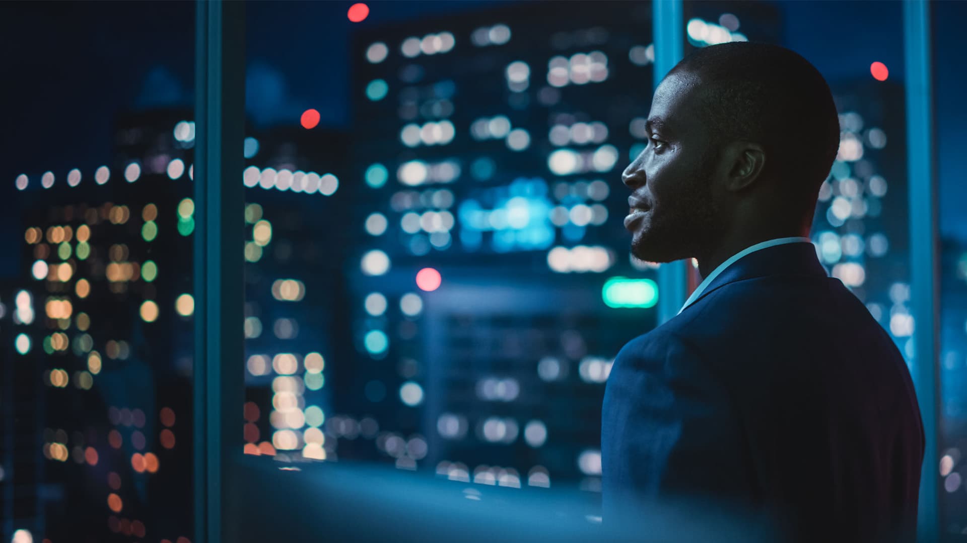 Successful Businessman Looking Out of the Window on Late Evening.