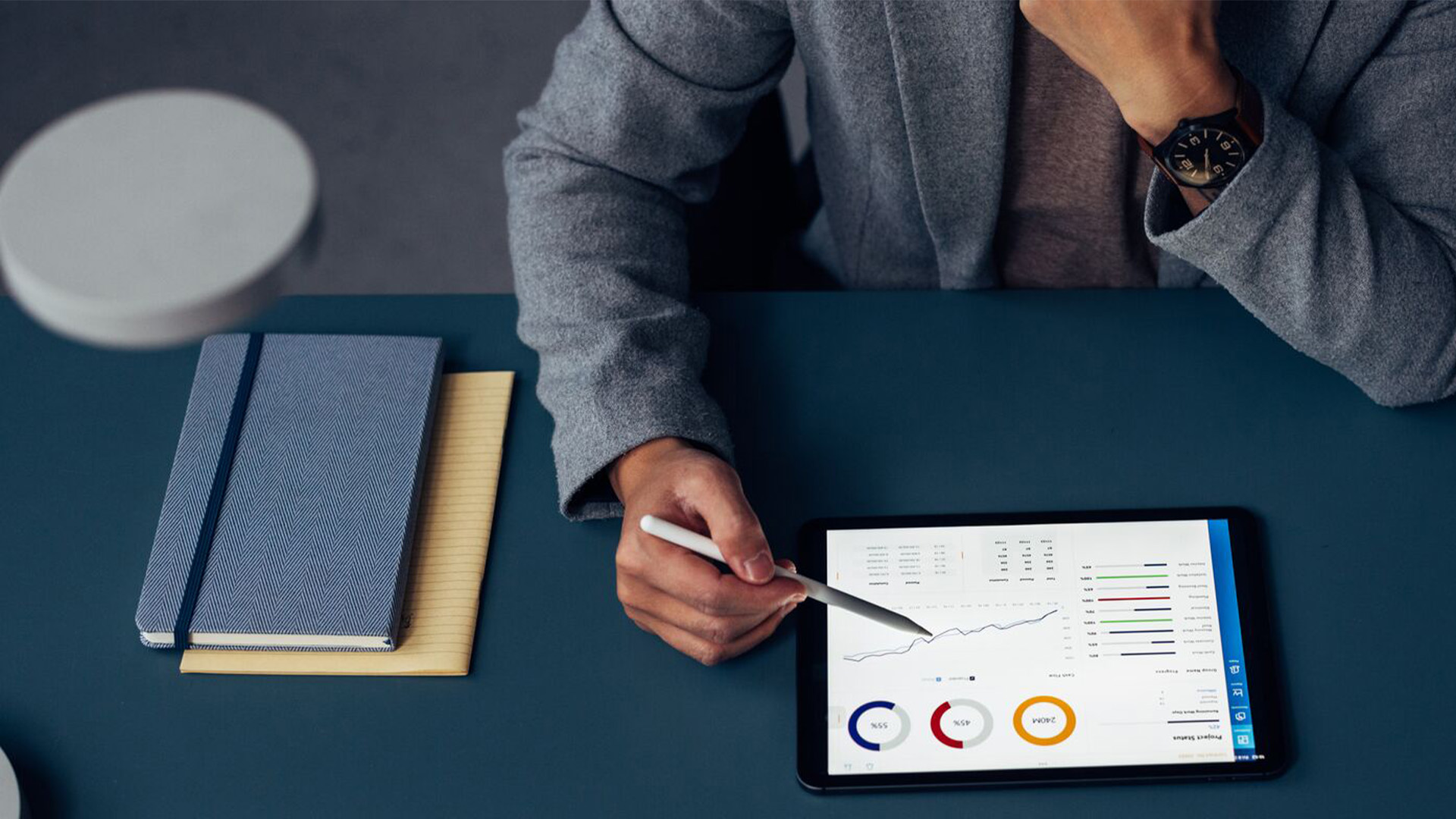 A man looking at stats on a tablet at a desk.