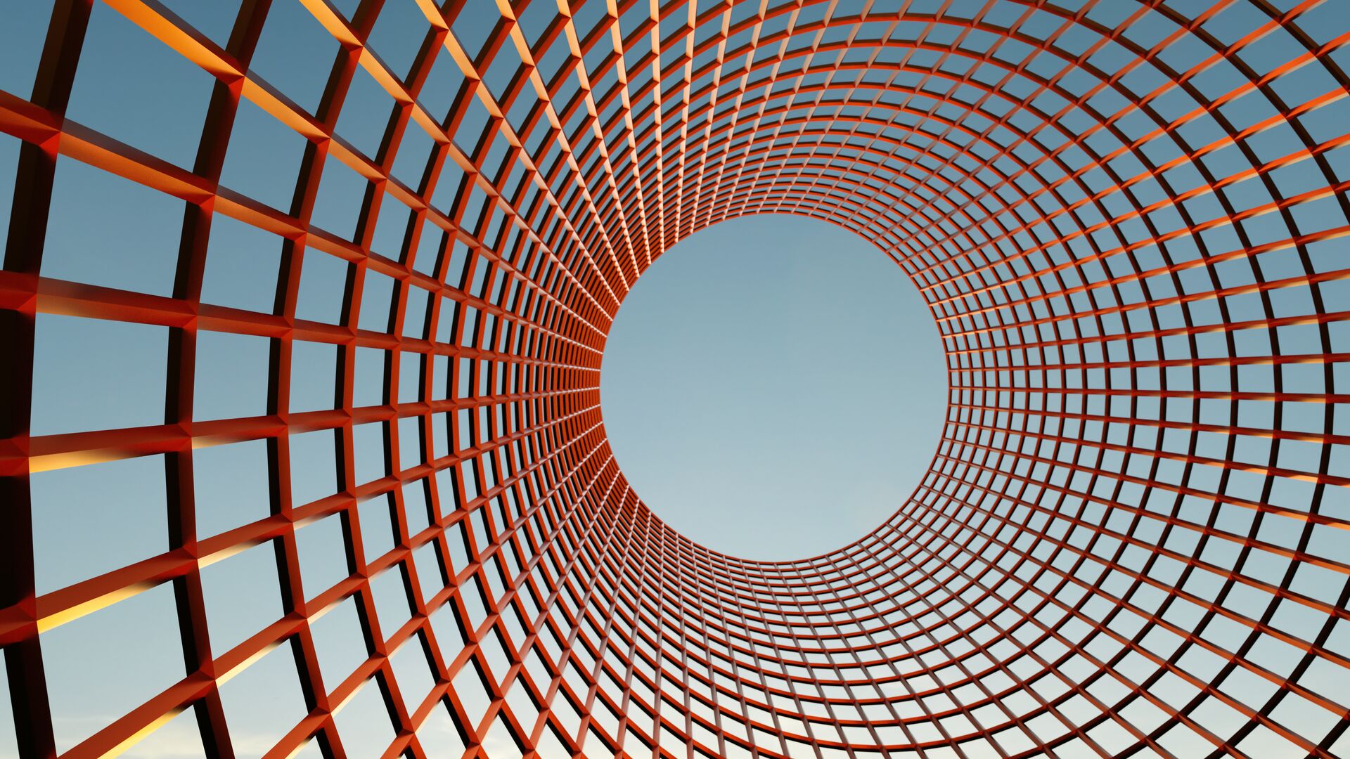 A circular red-orange metal lattice curves upward around a large central opening against a blue sky.