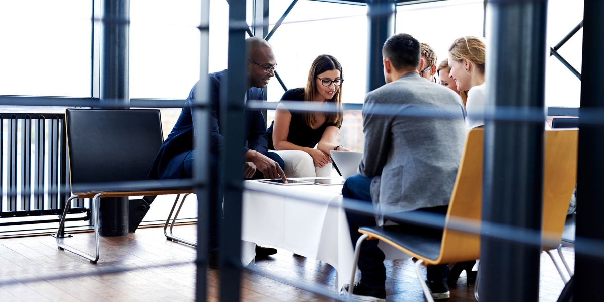 Colleagues gathered around a desk in a bright conference room.