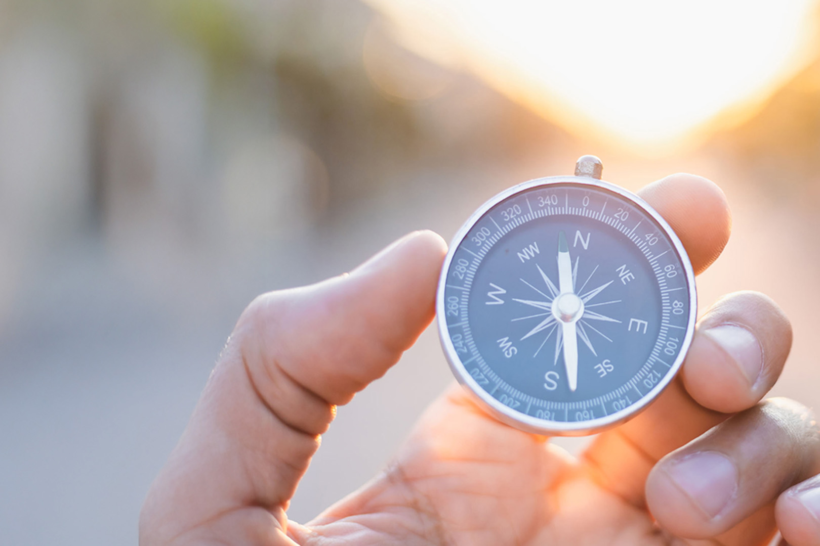A person holding a compass on a blurred background