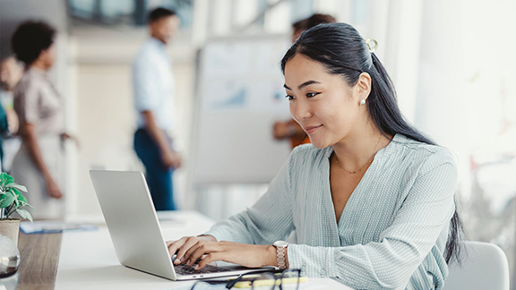 A woman typing on her laptop in an office.