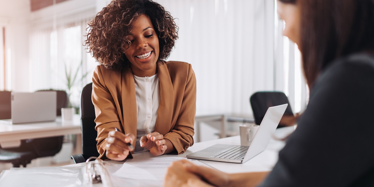 Two women speaking while looking over a binder of notes