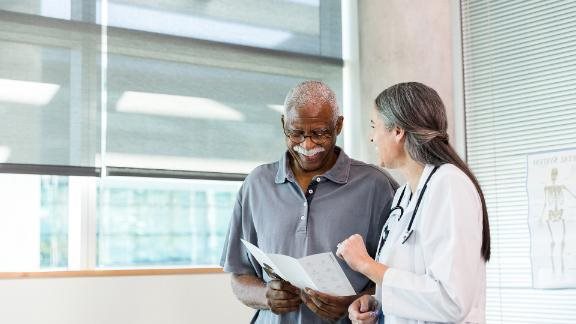 A doctor and her patient who are smiling as they discuss about information in a brochure