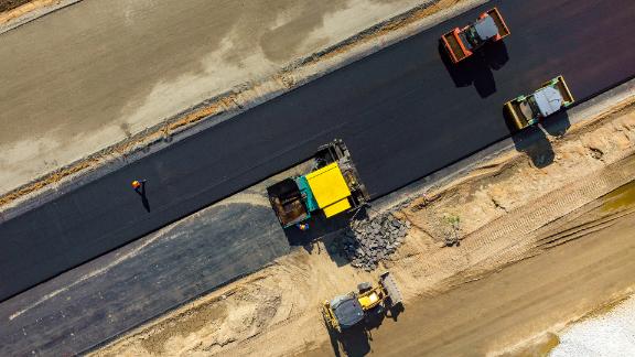 A few road rollers working on the new road on a construction site.