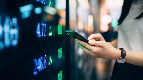 Close up of young businesswoman checking financial trading data on smartphone.