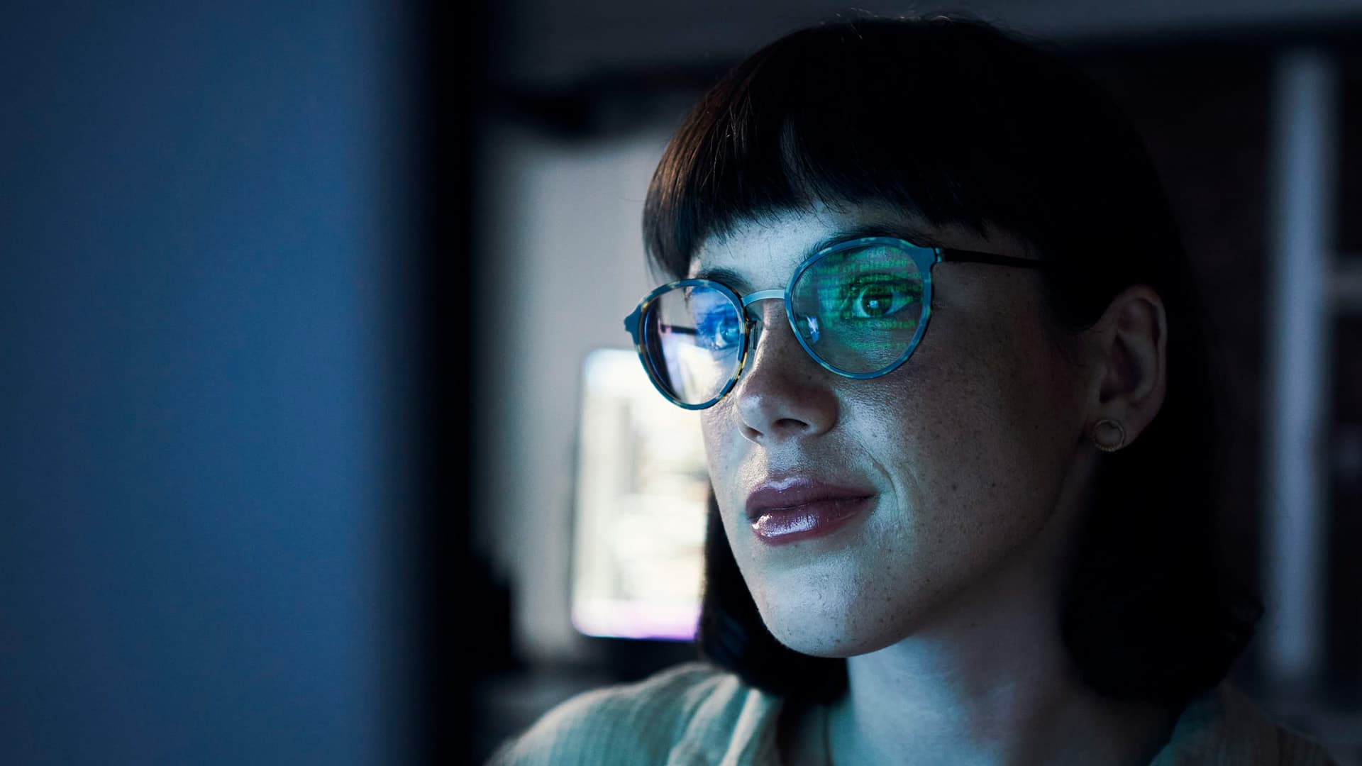 A woman looking at code on a computer screen.