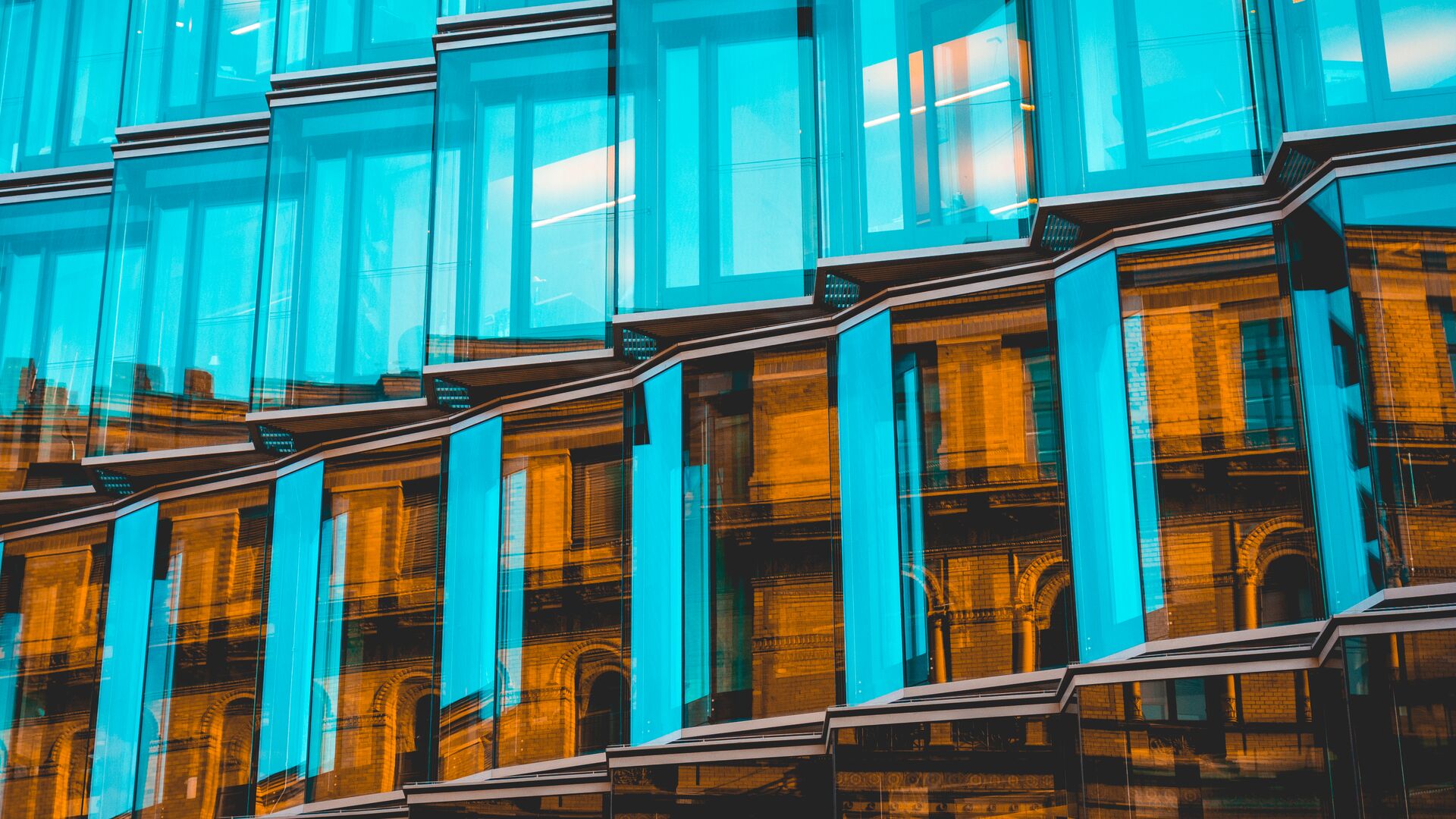 The exterior of a shining glass building in a city.