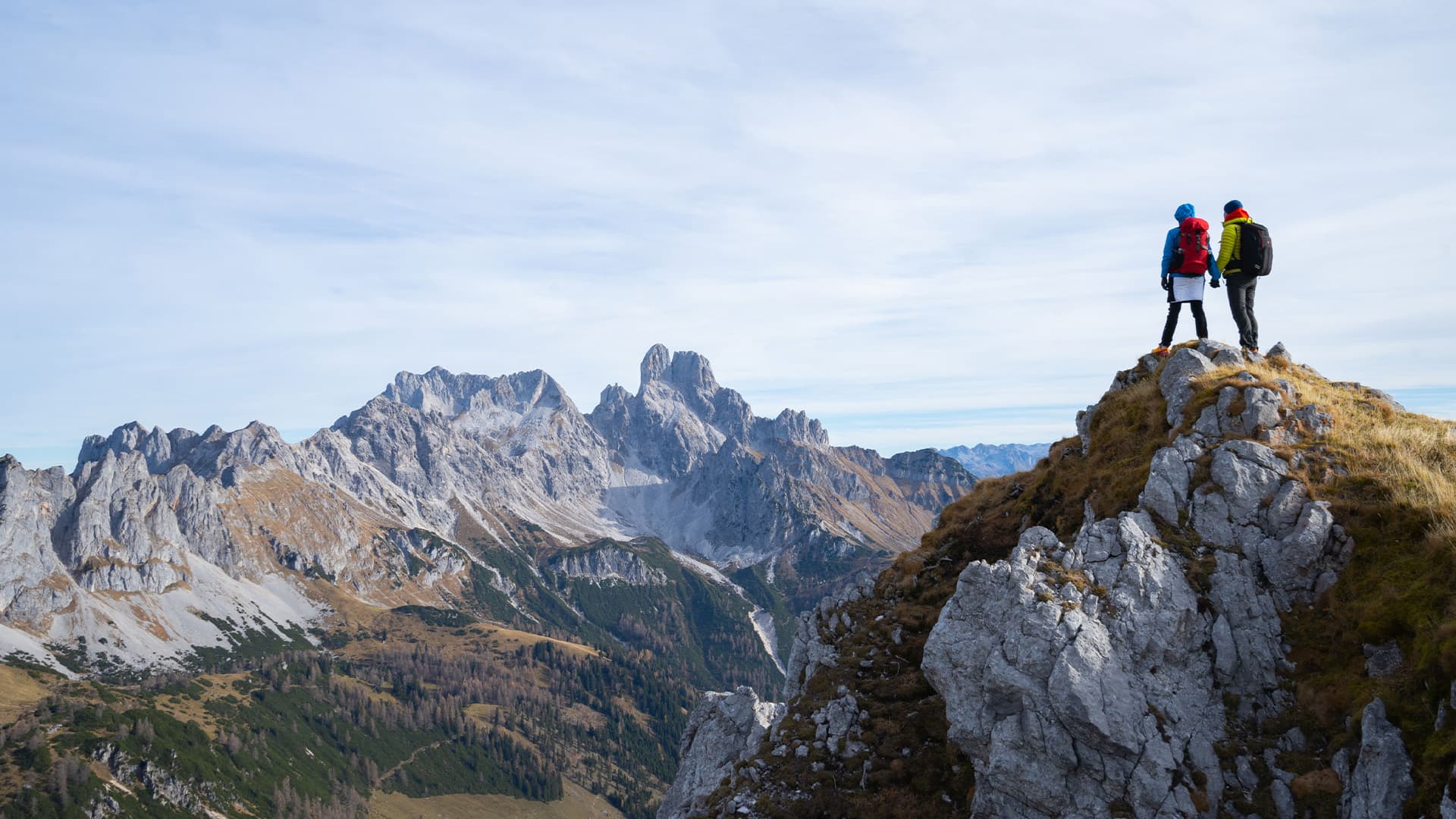A couple holding hands while admiring the view from a mountain top.