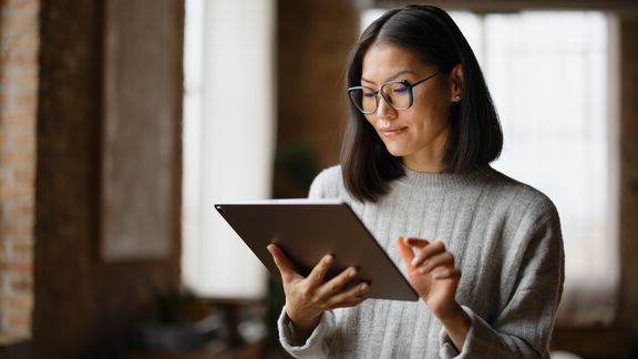 A women who is in an office and working on a digital tablet while standing