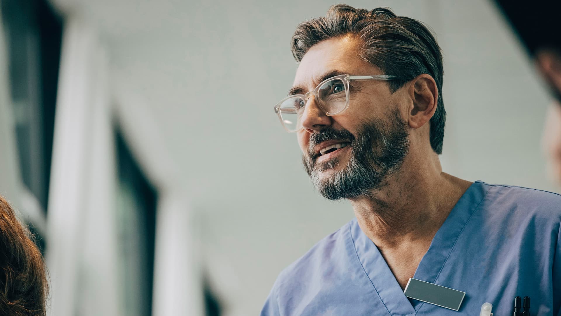 A smiling male doctor who is wearing eyeglasses in a hospital