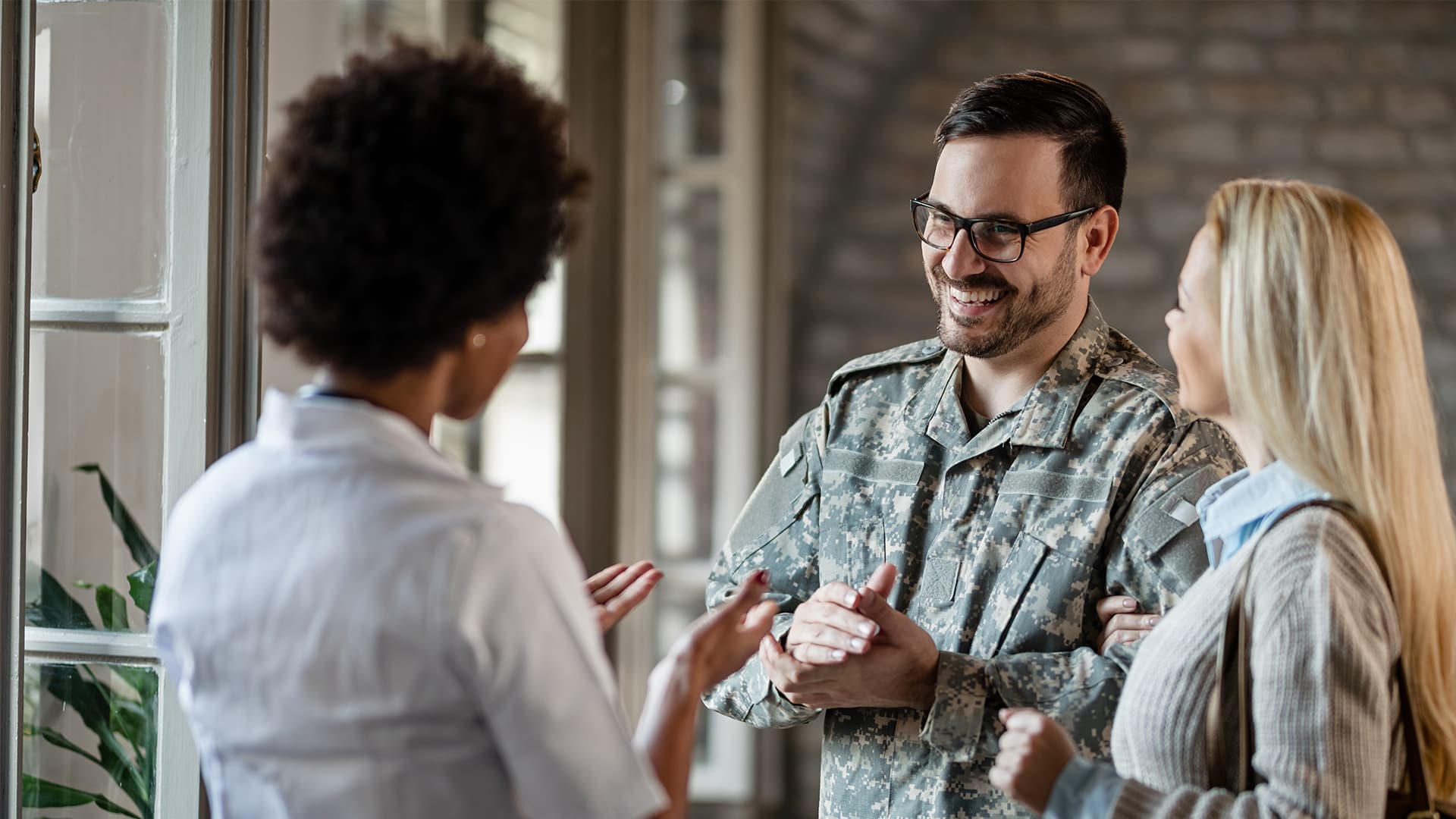 Happy military man and his wife talking to a doctor at medical clinic.