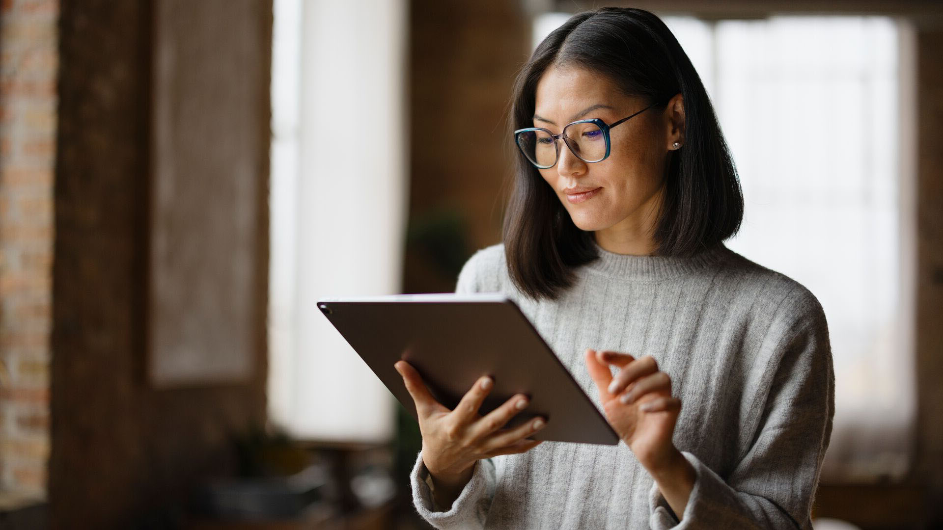 A women who is in an office and working on a digital tablet while standing