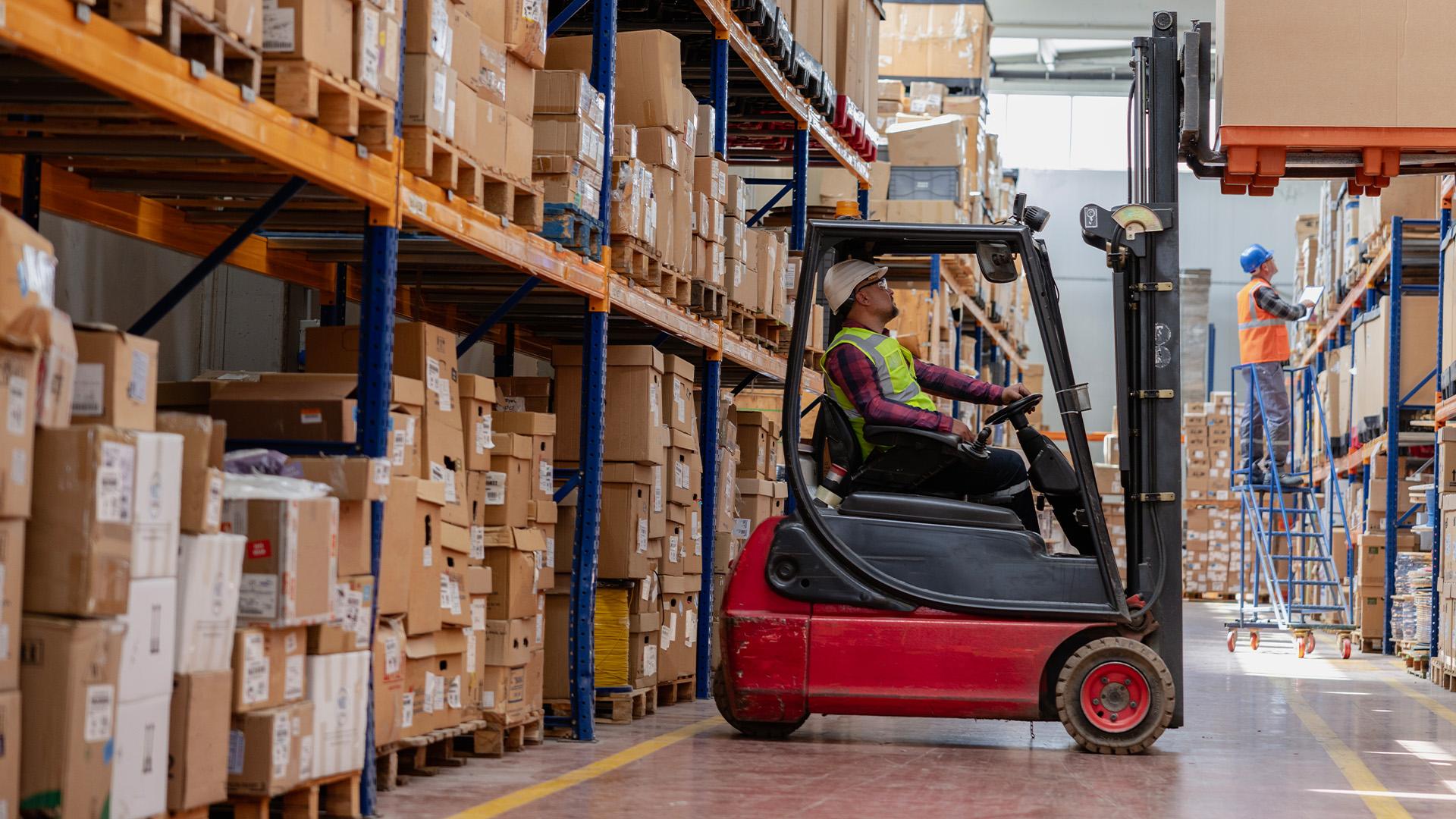 A worker using heavy machinery to move large pallets around.