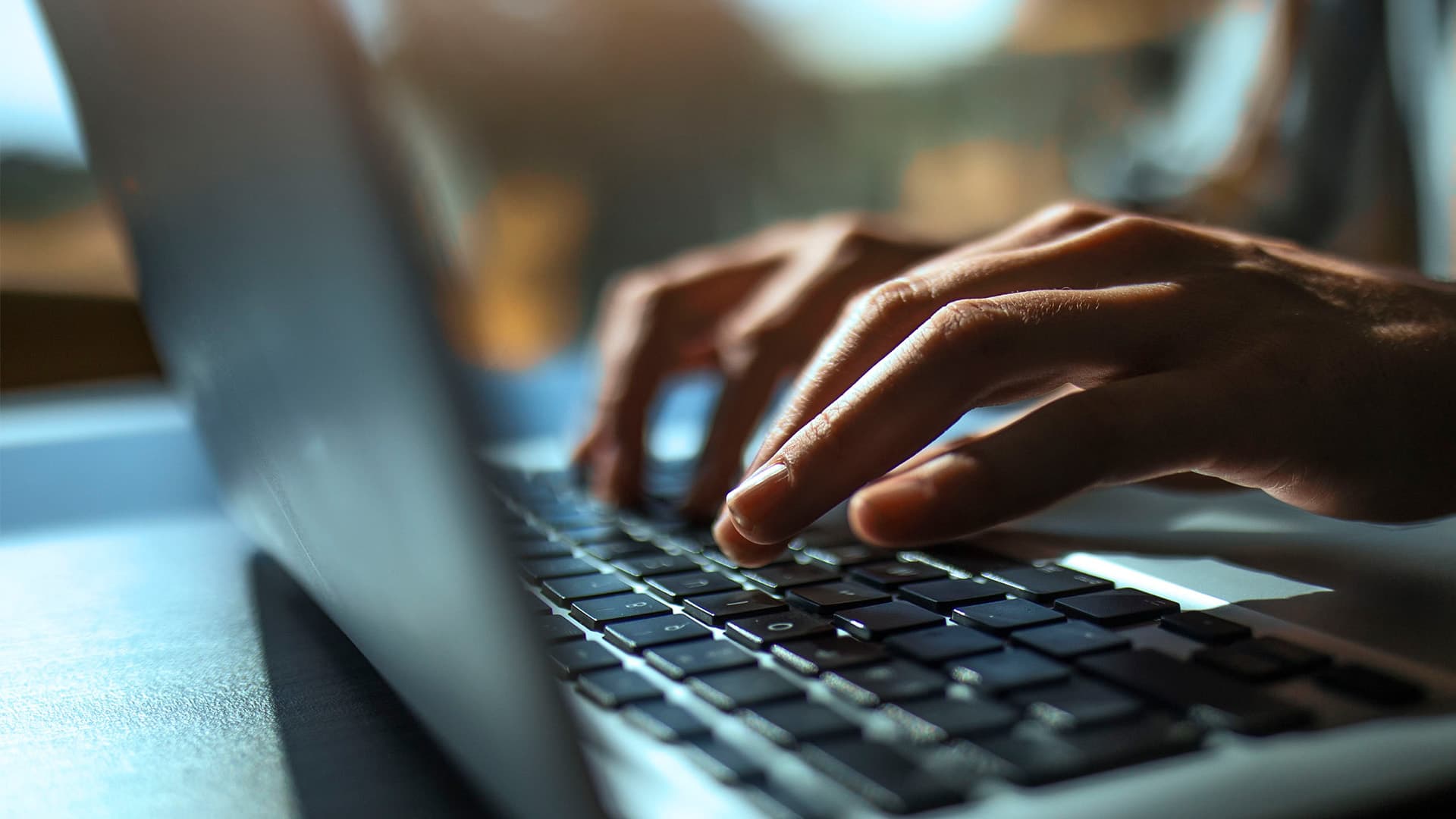 A person typing on their laptop keyboard