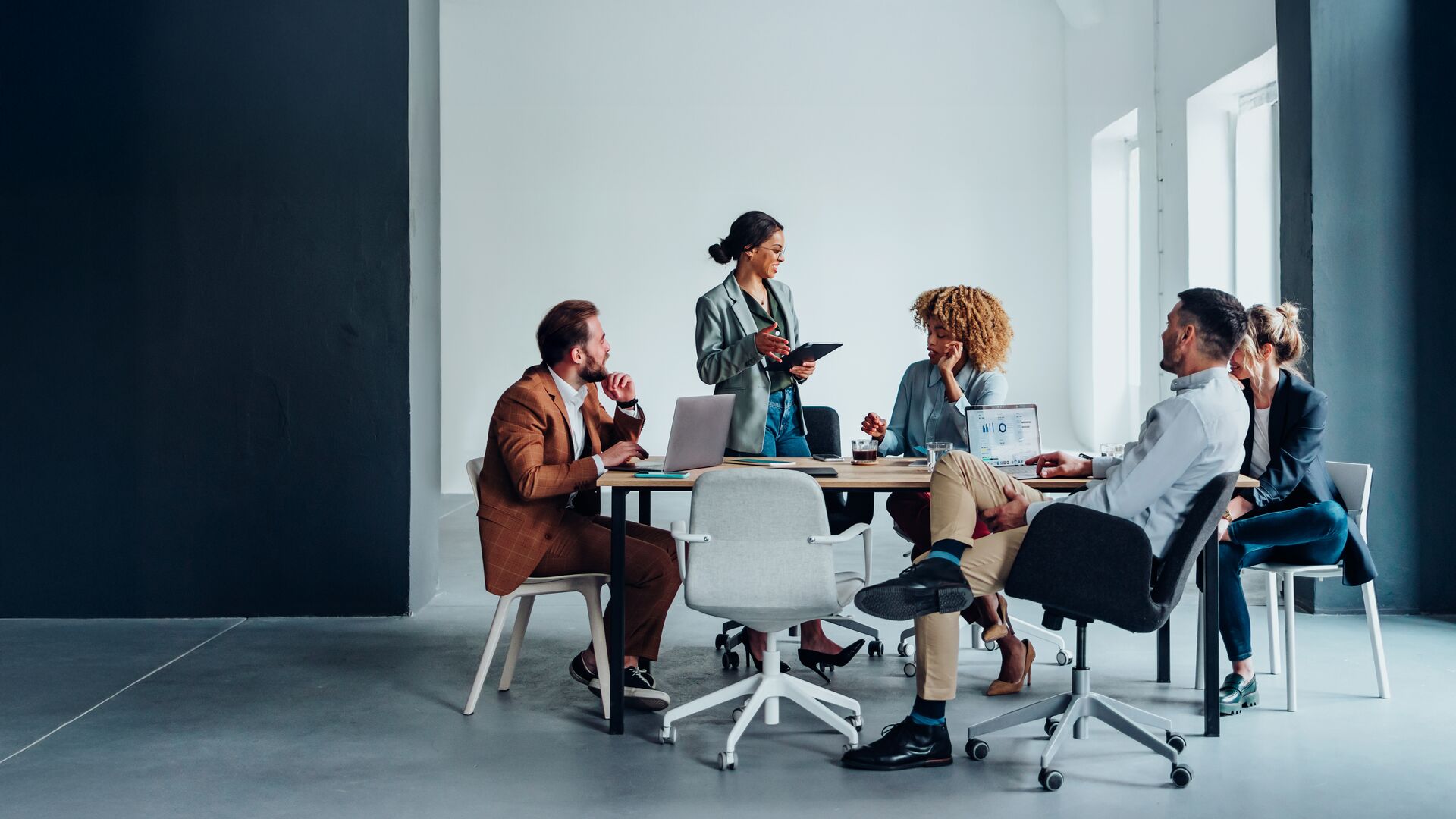 A group of people who are sitting at a table with laptops and having a discussion