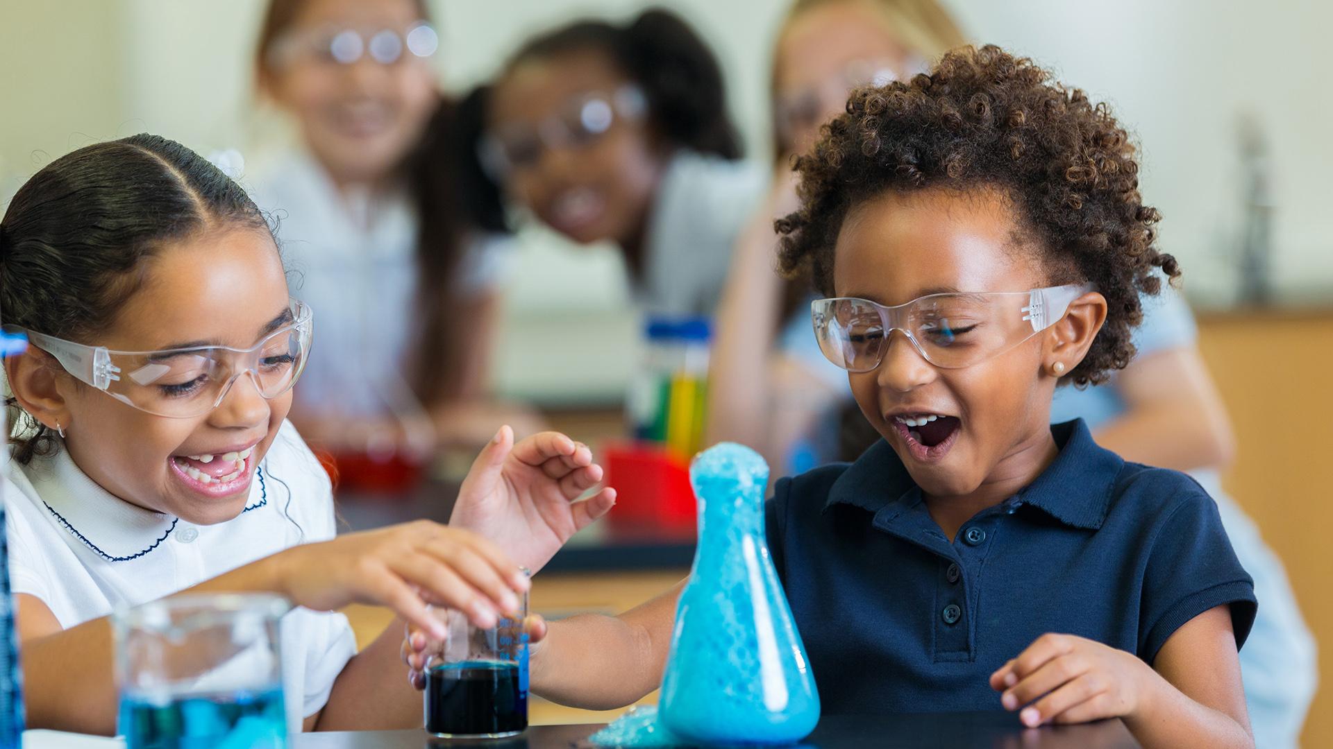 Diverse private school classmates are excited as foam overflows from beaker during chemistry experiment.