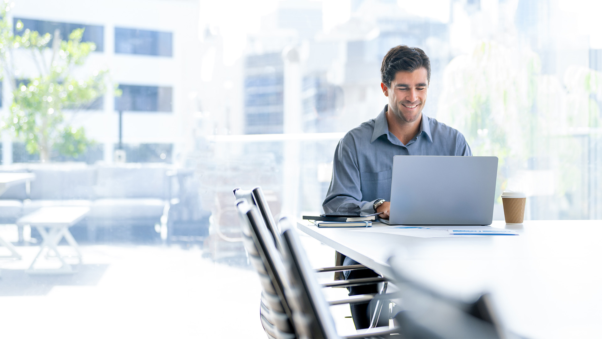 Smiling and satisfied business man working on his laptop in a bright office space.