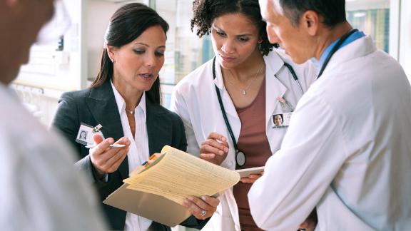 Two doctors discuss paperwork with an administrator.