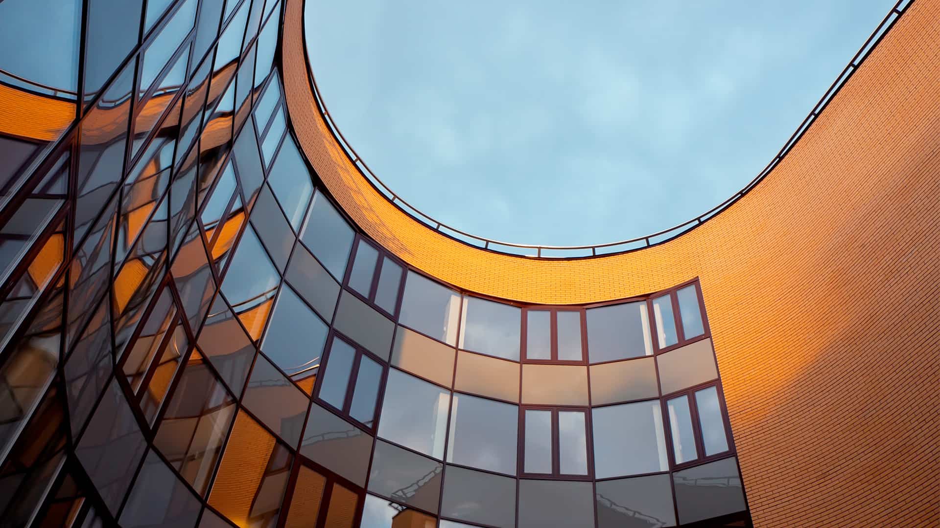 The front of a modern looking building with glass windows and brick visible